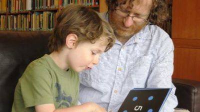 Young child reading a Mathical book with his father