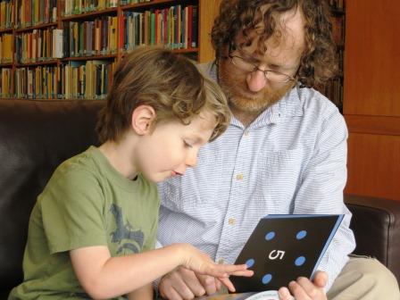 Young child reading a Mathical book with his father