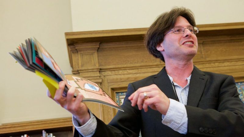 Mathical author holding up his book as he reads it